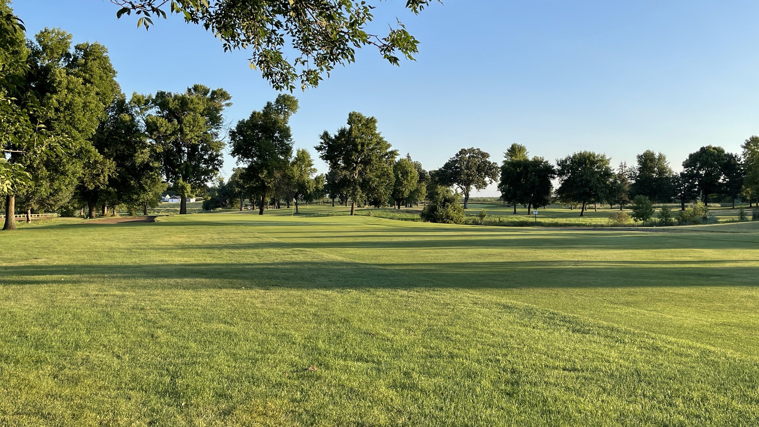 A tree-lined fairway under a clear sky at Montgomery National Golf Club