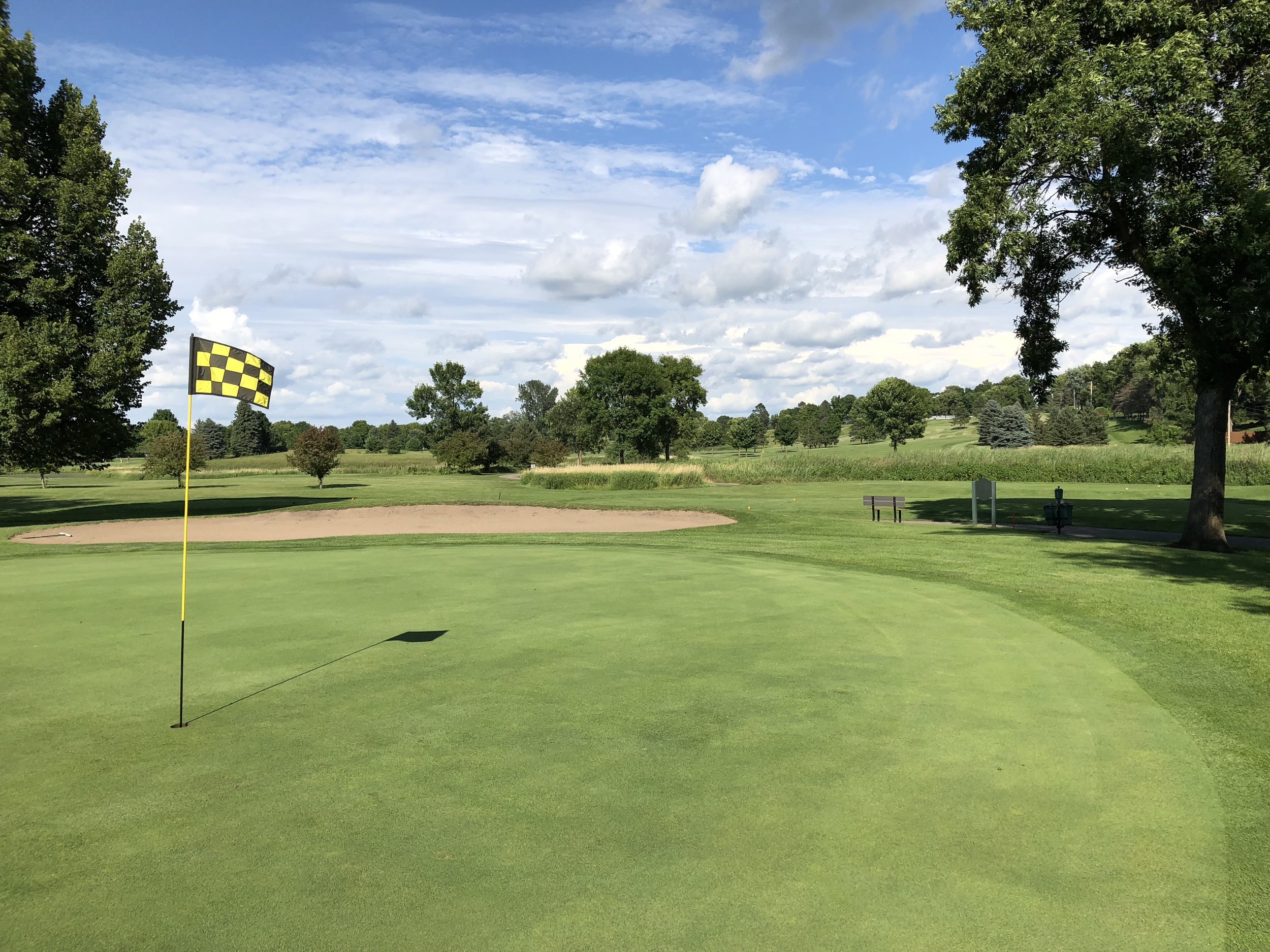 A flagged green with a sand bunker behind it at Montgomery National Golf Club